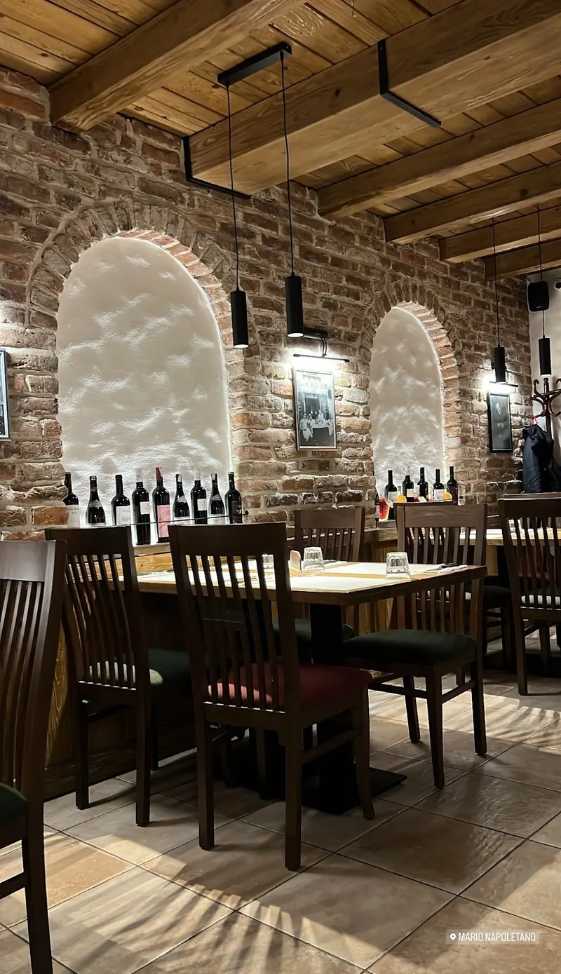 Dining room with wooden tables, lit white arches and a row of wine bottles