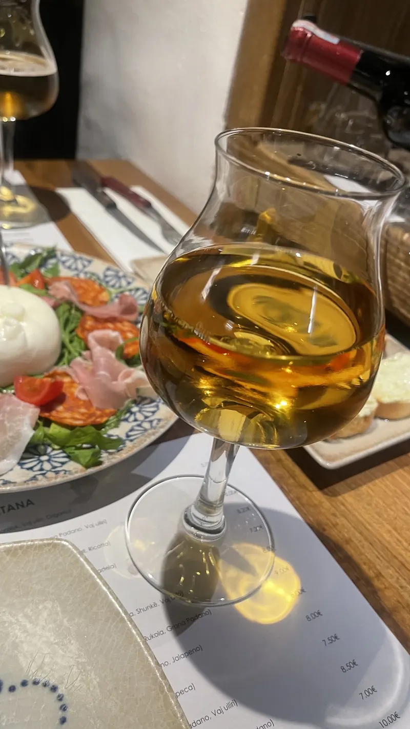 Burrata with prosciutto and cherry tomatoes next to a glass of craft beer