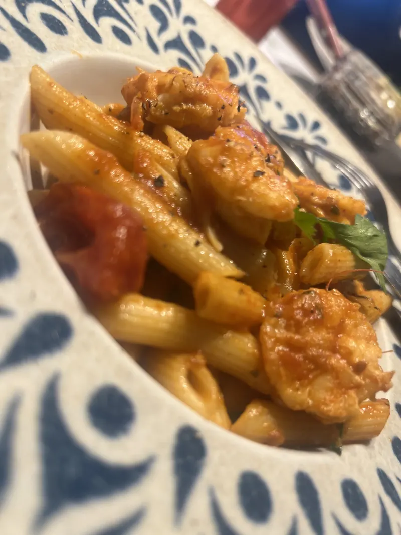 Penne with shrimp in tomato sauce on a blue and white patterned plate