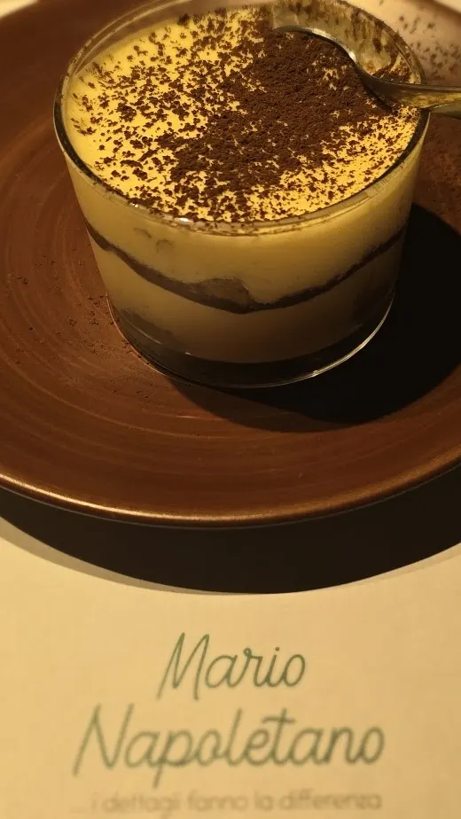 Tiramisu in a glass dusted with cocoa, on a brown plate